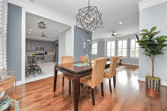 dining area with crown molding, baseboards, ceiling fan with notable chandelier, and light wood-style floors