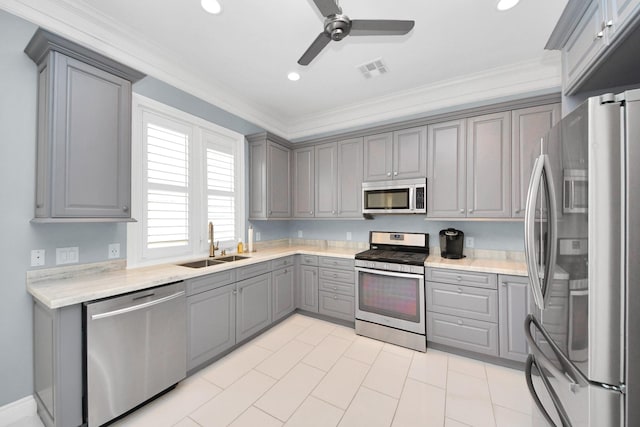 kitchen with gray cabinets, a ceiling fan, crown molding, a sink, and stainless steel appliances