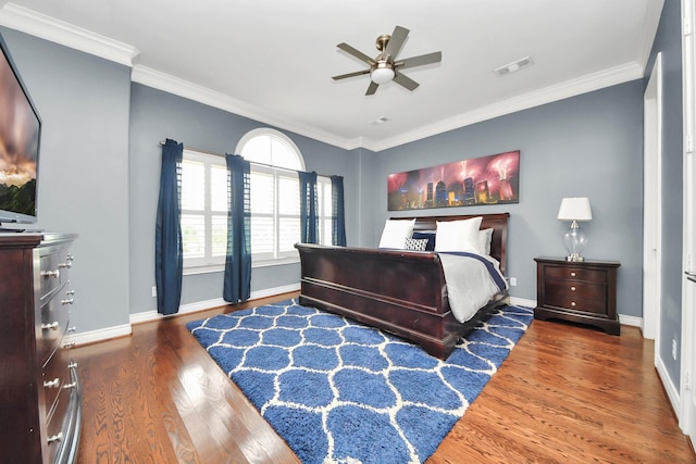 bedroom featuring crown molding, baseboards, visible vents, and wood finished floors