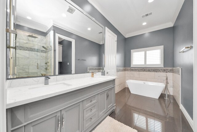 bathroom with visible vents, tile walls, a shower stall, a sink, and ornamental molding