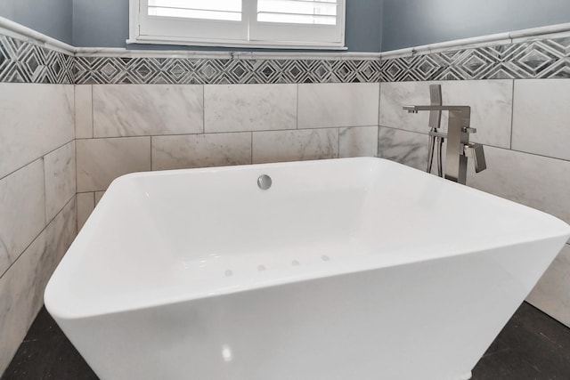 bathroom featuring a freestanding tub and tile walls