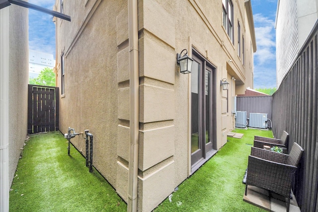 view of side of home with fence, central AC unit, and stucco siding