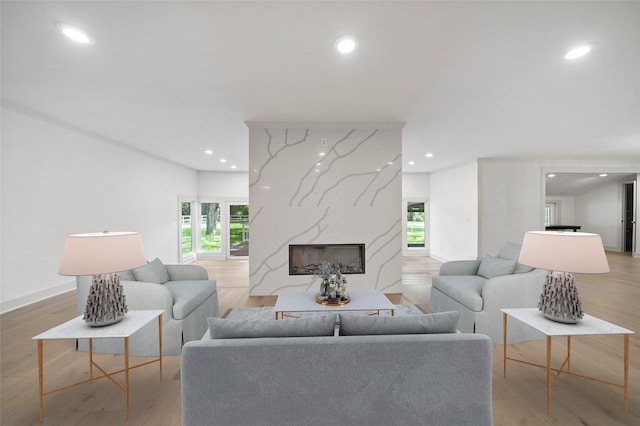 living room featuring a high end fireplace, baseboards, light wood-type flooring, and recessed lighting