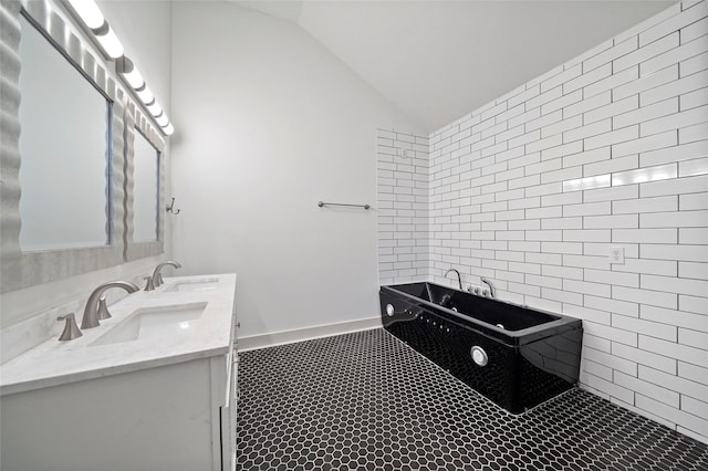 bathroom with vaulted ceiling, a freestanding tub, a sink, and double vanity
