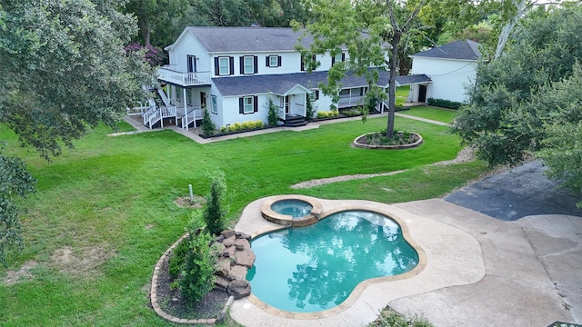 exterior space featuring a lawn, roof with shingles, a pool with connected hot tub, and a balcony