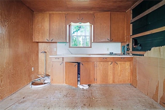 kitchen with light countertops, brown cabinetry, wood walls, and wood ceiling