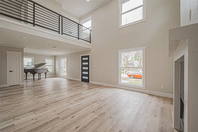 2102 Banks St, Houston, TX 77098 - unfurnished living room featuring baseboards, a towering ceiling, light wood-style floors, and ornamental molding