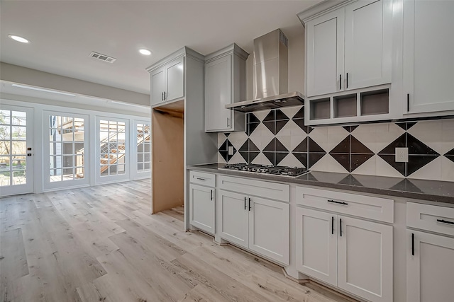 2102 Banks St, Houston, TX 77098 - kitchen with stainless steel gas cooktop, tasteful backsplash, light wood-type flooring, visible vents, and wall chimney range hood