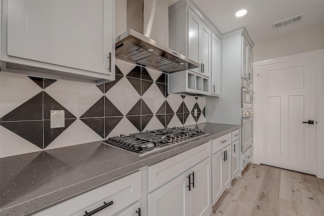 2102 Banks St, Houston, TX 77098 - kitchen with white cabinetry, wall chimney exhaust hood, appliances with stainless steel finishes, and visible vents