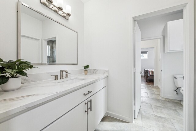 bathroom with tile patterned flooring, vanity, toilet, and baseboards