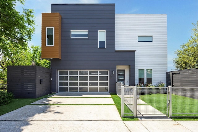 modern home with a gate, a front lawn, driveway, an attached garage, and fence