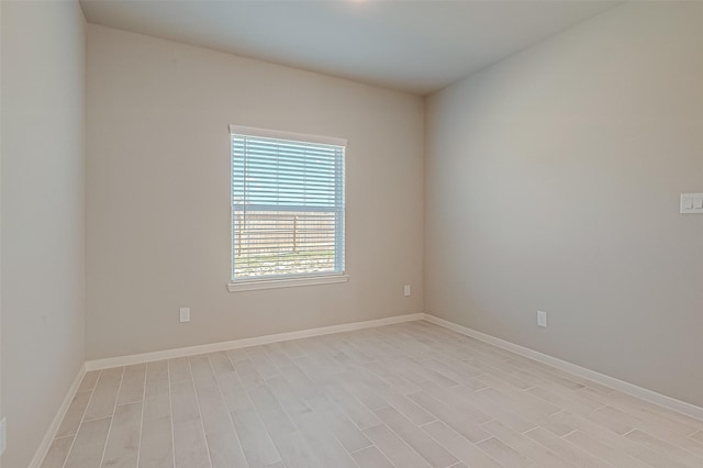 spare room featuring baseboards and light wood finished floors