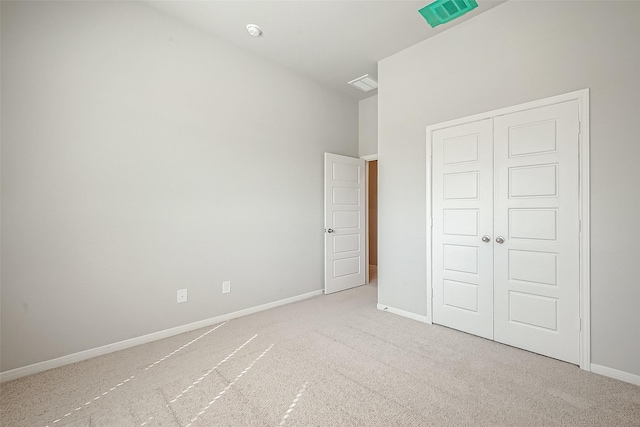 unfurnished bedroom with light colored carpet, baseboards, visible vents, and a closet