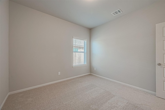 spare room with baseboards, visible vents, and light colored carpet