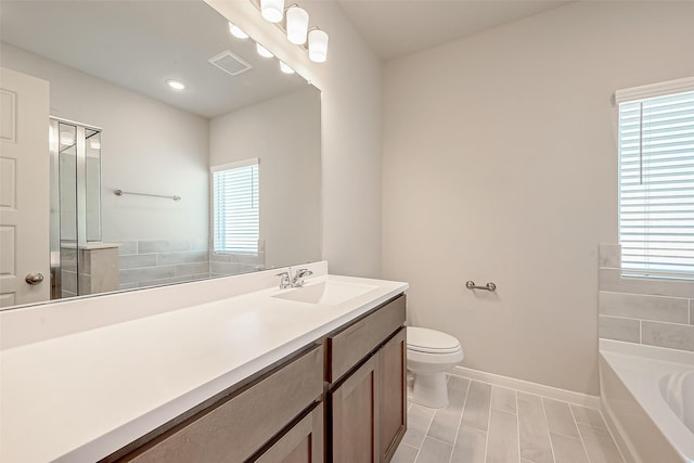 bathroom with a garden tub, visible vents, toilet, and a wealth of natural light