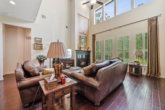 living area featuring baseboards, dark wood-style flooring, a towering ceiling, and visible vents