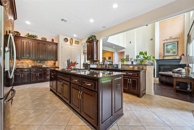 kitchen featuring stainless steel appliances, visible vents, light tile patterned flooring, a kitchen island, and decorative backsplash