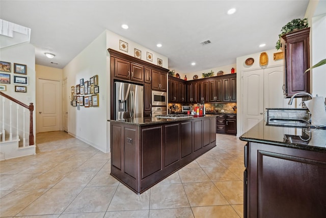 kitchen featuring decorative backsplash, light tile patterned flooring, stainless steel appliances, and a sink