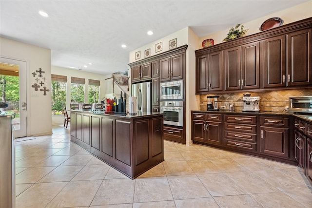 kitchen with tasteful backsplash, a kitchen island with sink, light tile patterned floors, appliances with stainless steel finishes, and recessed lighting