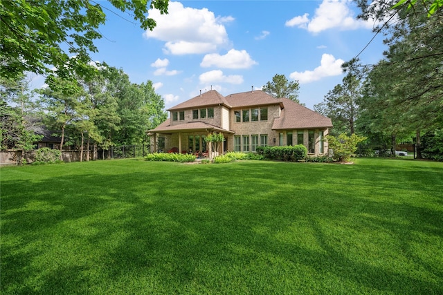 back of property featuring fence, brick siding, and a yard