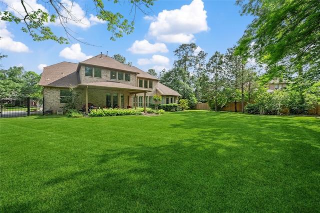 back of property with a lawn and fence