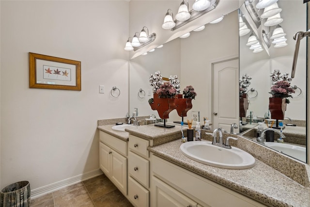 full bath with double vanity, baseboards, and a sink