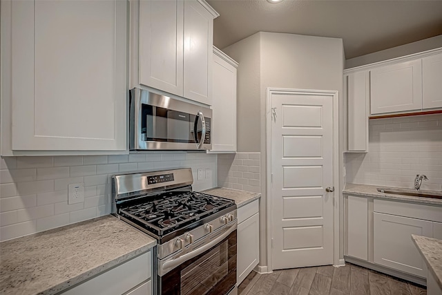 2128 Port Jackson, Texas City, TX 77568 - kitchen featuring stainless steel appliances, white cabinetry, a sink, tasteful backsplash, and light stone countertops
