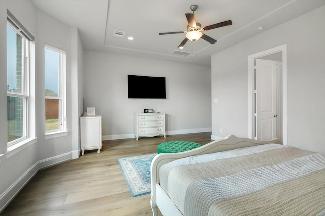 bedroom with baseboards, a ceiling fan, visible vents, and light wood-style floors