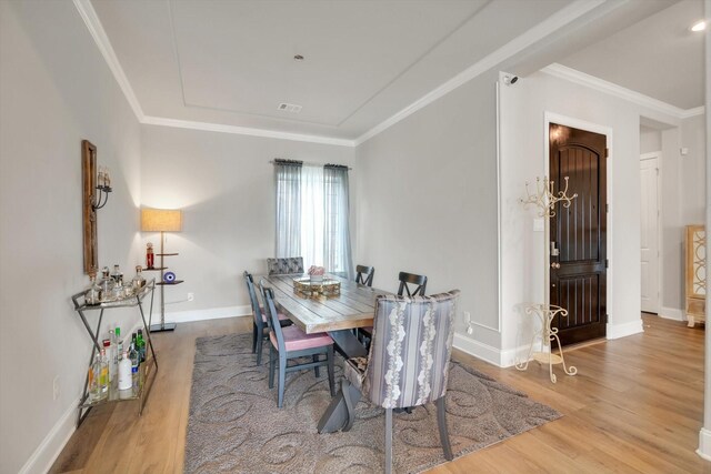 dining space with baseboards, ornamental molding, wood finished floors, and visible vents