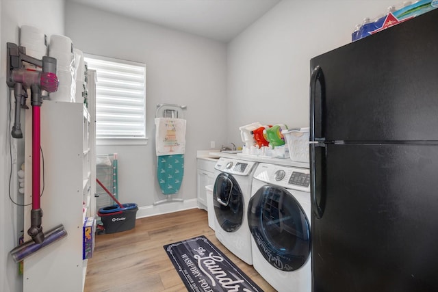 clothes washing area with separate washer and dryer, baseboards, a sink, and light wood-style floors