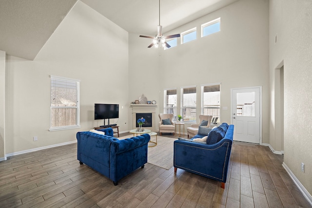 32610 Dew Crest St, Brookshire, TX 77423 - living area featuring a towering ceiling, wood finished floors, a ceiling fan, baseboards, and a glass covered fireplace