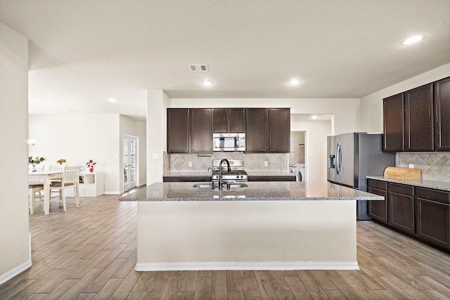 32610 Dew Crest St, Brookshire, TX 77423 - kitchen featuring dark brown cabinets, stainless steel appliances, light wood finished floors, washing machine and dryer, and visible vents