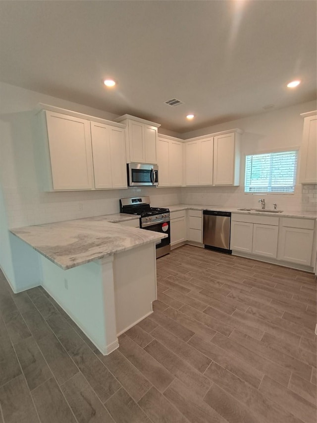 12367 Sterling Oak, Humble, TX 77044 - kitchen featuring stainless steel appliances, a sink, white cabinets, a peninsula, and recessed lighting