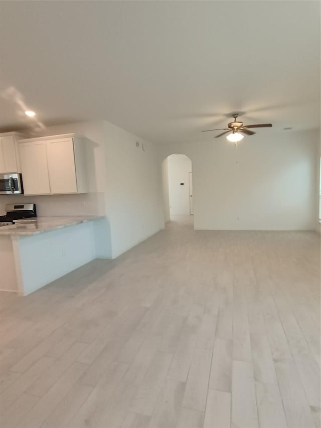 12367 Sterling Oak, Humble, TX 77044 - kitchen with stainless steel microwave, arched walkways, a ceiling fan, open floor plan, and recessed lighting