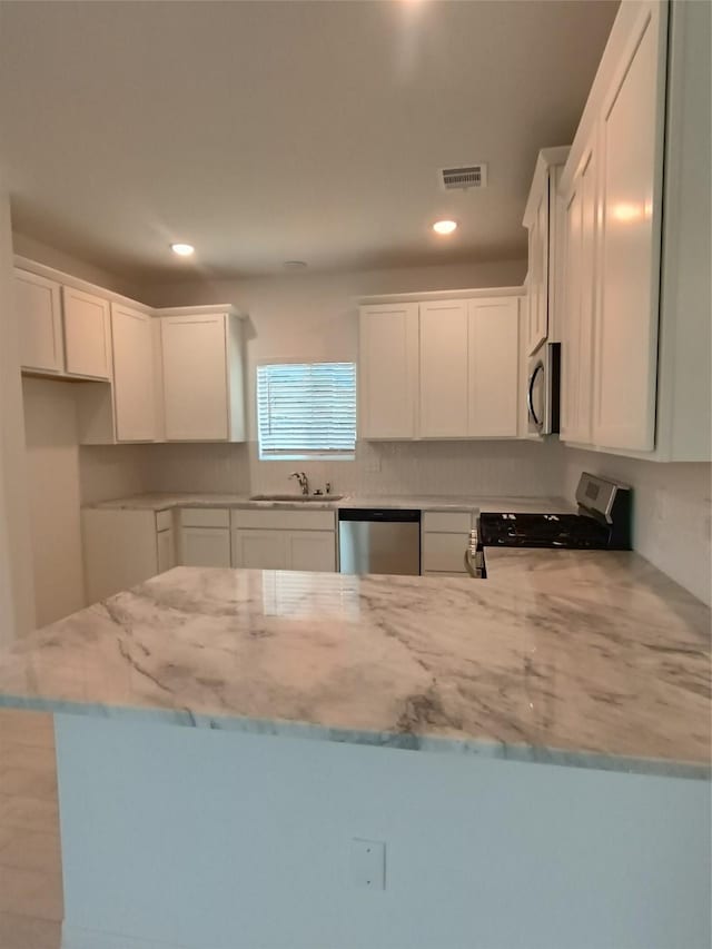 12367 Sterling Oak, Humble, TX 77044 - kitchen featuring stainless steel appliances, light stone countertops, a sink, a peninsula, and white cabinetry