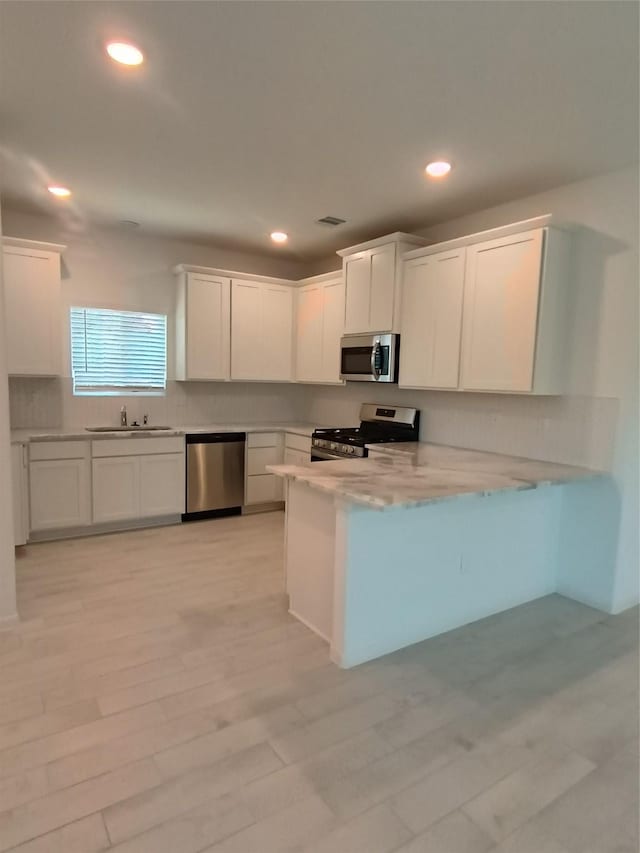 12367 Sterling Oak, Humble, TX 77044 - kitchen with stainless steel appliances, a sink, white cabinets, decorative backsplash, and a peninsula