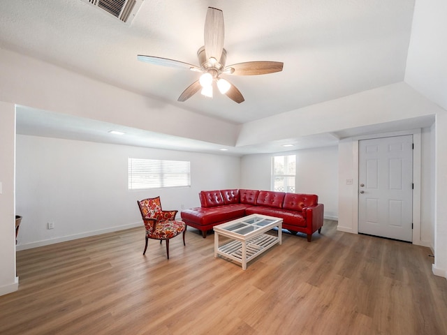 living room with visible vents, ceiling fan, light wood finished floors, and baseboards