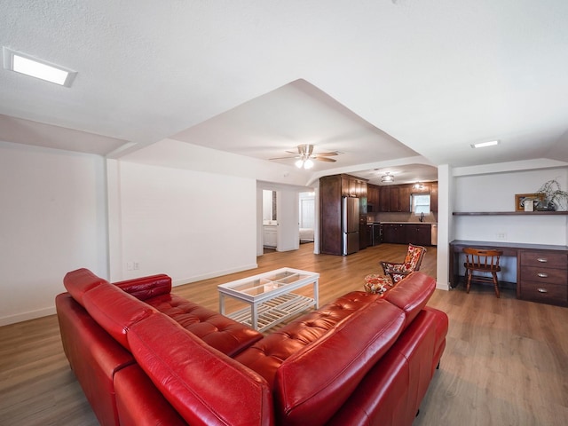 living area with ceiling fan, light wood-style flooring, and baseboards