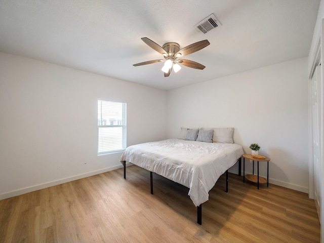 bedroom with baseboards, visible vents, a ceiling fan, and light wood finished floors