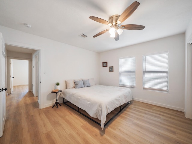 bedroom featuring ceiling fan, visible vents, light wood-type flooring, and baseboards