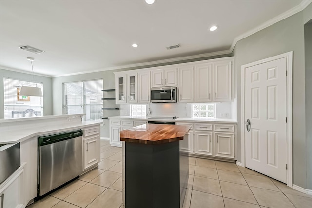 kitchen with wood counters, light tile patterned floors, stainless steel appliances, white cabinetry, and visible vents
