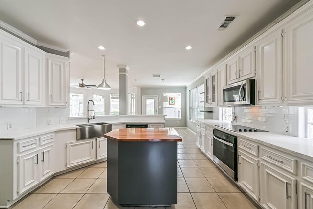 kitchen featuring a sink, wooden counters, a peninsula, appliances with stainless steel finishes, and visible vents