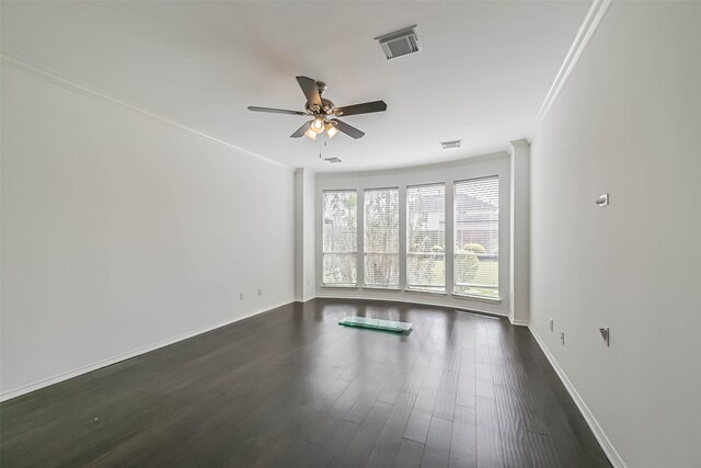 empty room with a ceiling fan, crown molding, baseboards, dark wood-type flooring, and visible vents