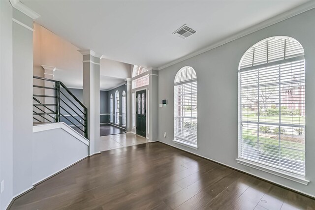 entryway with visible vents, ornate columns, wood finished floors, stairs, and ornamental molding