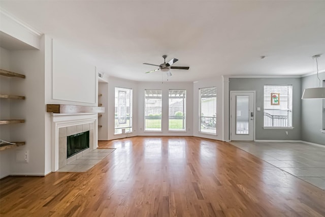 unfurnished living room featuring baseboards, a ceiling fan, wood finished floors, and a fireplace