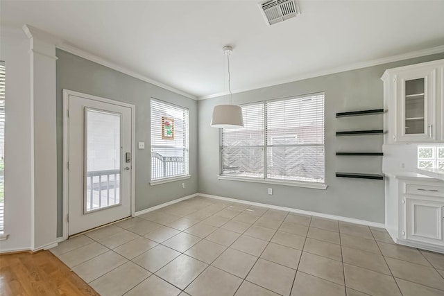 unfurnished dining area featuring light tile patterned floors, baseboards, visible vents, and ornamental molding