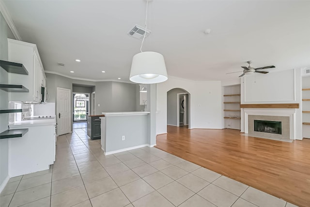 unfurnished living room with recessed lighting, light tile patterned flooring, arched walkways, a tiled fireplace, and ceiling fan