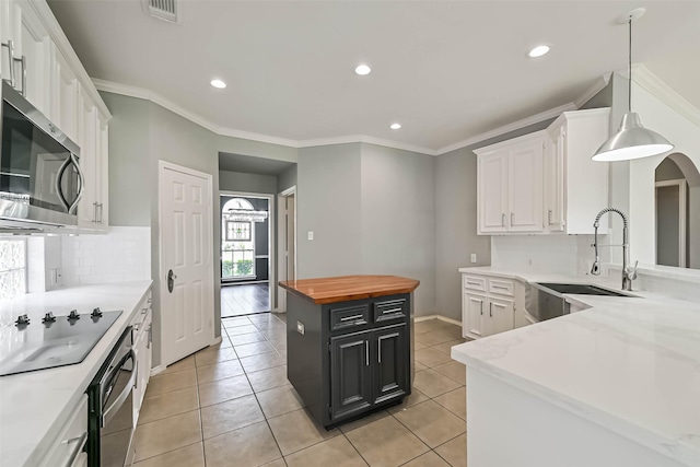 kitchen with black electric cooktop, visible vents, a sink, stainless steel microwave, and white cabinetry