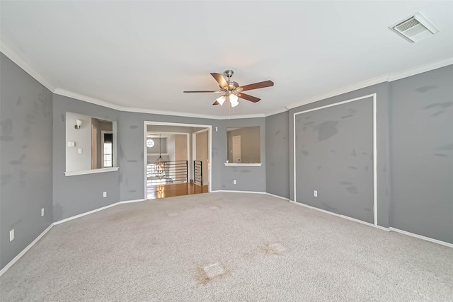 spare room with ceiling fan, carpet, baseboards, ornamental molding, and visible vents