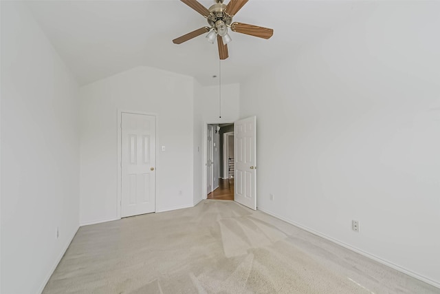 unfurnished bedroom featuring light carpet, vaulted ceiling, baseboards, and a ceiling fan